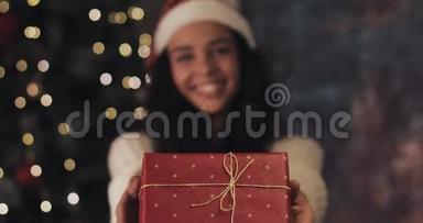 圣诞老人帽子里<strong>的</strong>快乐美丽<strong>的</strong>穆拉托女孩<strong>献礼</strong>和带回礼品盒，看着镜头和微笑站在